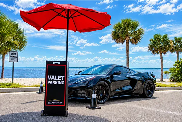 Black sports car parked beside an All Pro Valet valet parking sign at a Southwest Florida waterfront